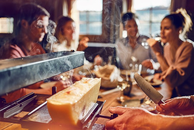 Valais, closeup of cheese being served to diners in a restaurant.