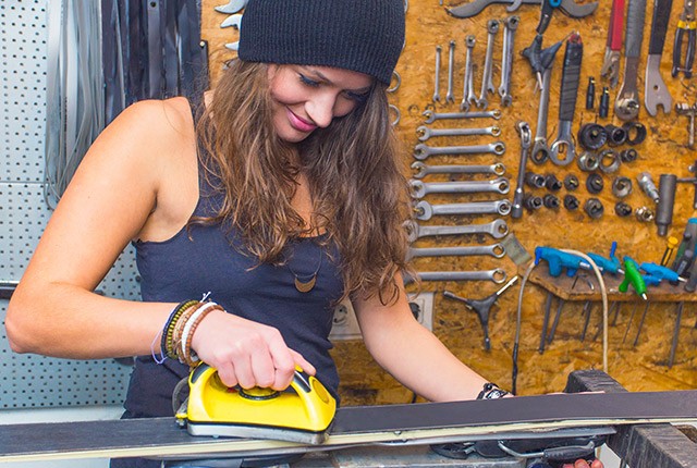 FR woman waxing skis, tuning in a shop.