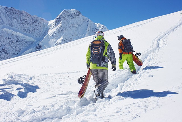 FR snowboarders hiking up a mountain.